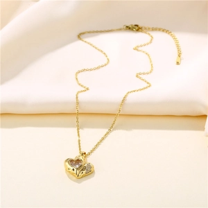 Gold heart necklace with sparkling zircon stone on beige soft fabric background