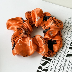 Detail of satin Halloween scrunchie with orange spider web, bat and ghost patterns