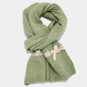 Detail of green knit scarf with cream bow decoration and soft textured winter fabric