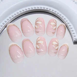 Pink and white gradient press-on nails with 3D floral accents and gold trim
