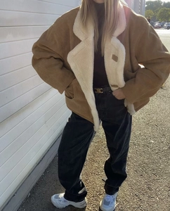Détail d'une veste en daim marron avec doublure en peau de mouton blanche et revers