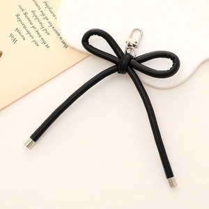 Chic black faux leather bow bag charm with a secure metal spring clasp accessory