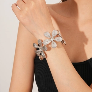 Makro-Detail eines silbernen Blumenarmband mit Kristallakzenten und geschichteten Blüten