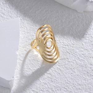 Macro shot of gold layered hollow geometric rings displayed on textured white stone blocks