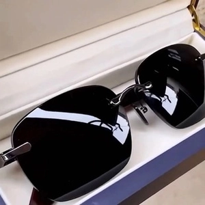 Close-up of rimless black oversized sunglasses with metal hinges in a premium navy blue case