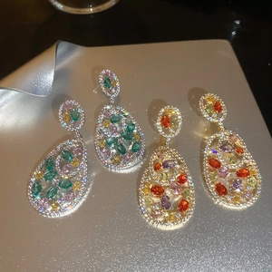 Macro shot of colorful hollow teardrop earrings with zircon stones on silver background
