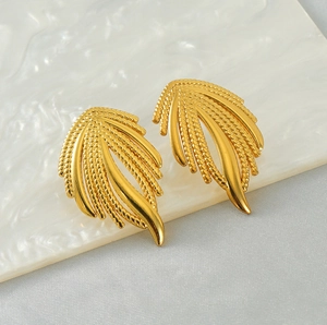 Détails de boucles d'oreilles plume dorées avec textures tressées et polies élégantes