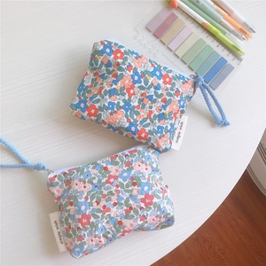 Detail of floral cotton mini pouch with zipper closure and blue woven wrist strap