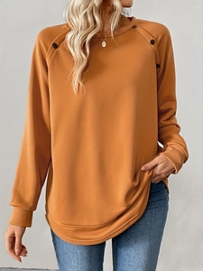 Detail of orange crewneck sweatshirt showing ribbed cuffs and shoulder button accents