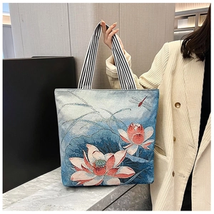 Detail of blue tote bag with red lotus pattern and black and white striped handles