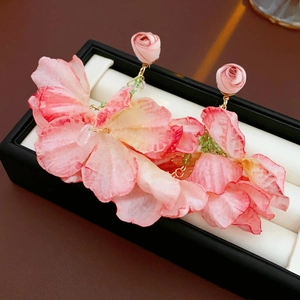 Makrodetail von Blumen-Mesh-Quastenohrringen mit rosa Verlauf in einer Schmuckschatulle