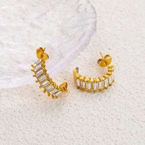 Detail of gold C-shaped earrings with rectangular cubic zirconia on water glass