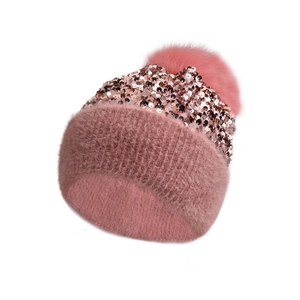 Macro detail of pink knit hat with rose gold sequins and a soft fluffy faux fur pompom