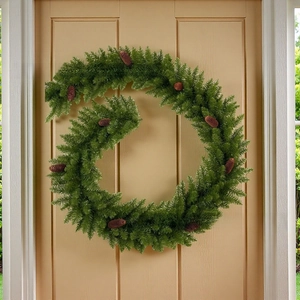 Vue détaillée d'une couronne de Noël artificielle avec pommes de pin sur porte en bois