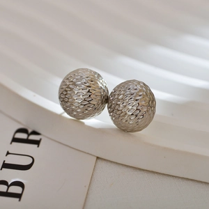 Macro detail of silver spherical earrings with textured honeycomb pattern on display stand