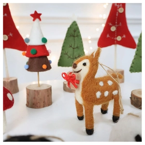 Macro shot of wool felt reindeer ornament with gift box and wooden base for Christmas