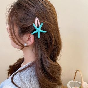 Detail of turquoise starfish hair clip on model featuring pink resin duckbill clip design