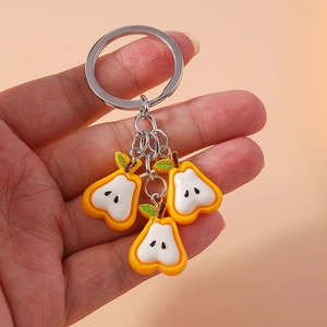 Cartoon pear fruit pendant keychain with silver ring held on pink background