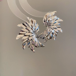 Macro detail of silver fan-shaped ripple earrings with a high-shine metallic mirror finish