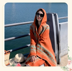 Detail view of a vibrant orange hooded ethnic shawl with heart patterns on a model