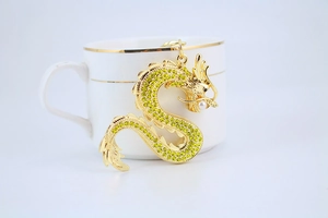 Détail d'un porte-clés dragon chinois doré avec strass jaunes et perle blanche