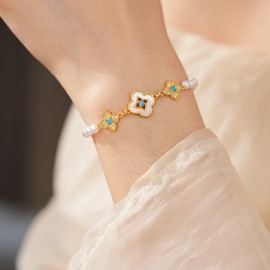 Dettaglio di un bracciale placcato oro 18k con zirconi blu, madreperla bianca e perle