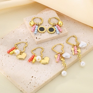 Golden heart earrings with pearls and Love pendant on silk and stone background