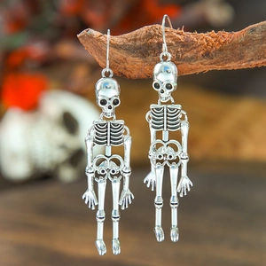 Gothic silver skull earring hanging on branch with a mystical vintage Halloween vibe