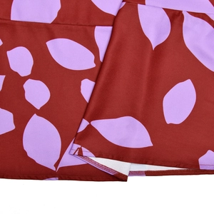 Détail du tissu en maille avec imprimé feuille violette sur robe marron rougeâtre