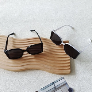 Close-up of black and white square oversized sunglasses on a decorative wooden tray