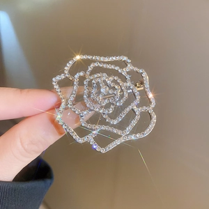 Macro detail of镂空 rose flower brooch with sparkling cubic zirconia on alloy metal
