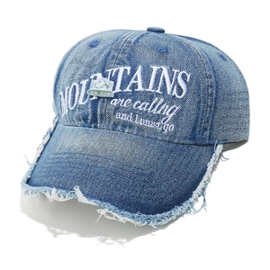 Detail of light blue denim baseball cap with frayed brim and white mountain embroidery