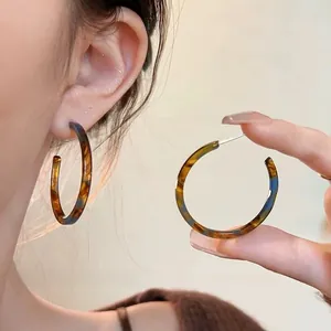 Detail of C-shaped tortoiseshell acrylic hoop earrings with polished vintage texture