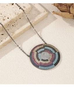 Macro shot of circular pendant with colorful stones on dark chain over a stone background