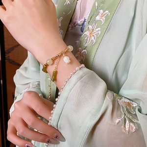 Détail du bracelet en bambou avec breloque pétale porté sur un hanfu en soie verte