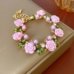 Détails du collier doré avec des roses roses, des perles violettes et un fermoir ajustable