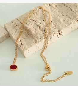 Detail of red agate pendant with gold bezel and K18 hallmark on titanium steel necklace