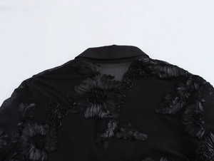Detail of 3D black floral embroidery on sheer mesh fabric of an elegant V-neck shirt