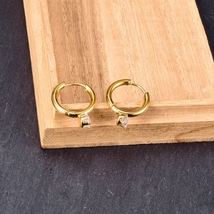 Classic gold six-prong stud earrings with clear zircon stones on a wooden tray
