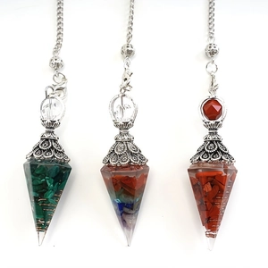 Three conical crystal pendulums with chakra stones and bronze carvings on white background