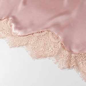 Détail du tissu en satin rose avec bordure en dentelle cil beige et texture lisse et soyeuse