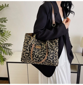 Detail of large leopard print canvas tote bag with brown PU leather straps worn by a model