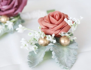 Macro detail of artificial rose boutonniere with gold beads and silver leaf for weddings