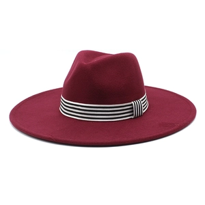 Detail of burgundy wide-brim wool fedora hat with black and white striped decorative band