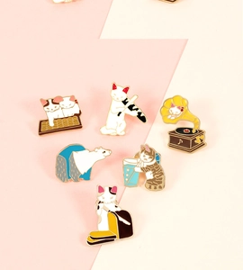 Set of six colorful enamel cat and bear pins shown on a pink and beige background