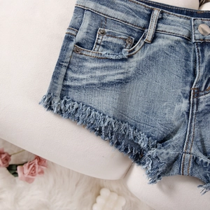 Detailaufnahme von blauen Denim-Shorts mit ausgefranstem Saum und Seitentaschen-Textur