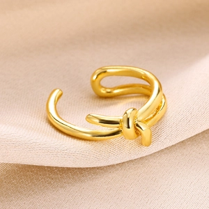 Macro view of gold plated knotted water drop ring on champagne silk background