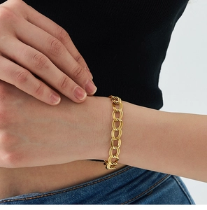 Dettaglio del bracciale a catena placcato oro con maglie intrecciate sul polso