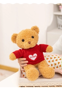 Détail d'ours en peluche avec pull en tricot rouge et broderie cœur LOVES