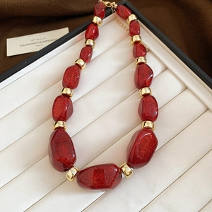 Detailed macro of red glitter acrylic beads and gold metal links on a display tray